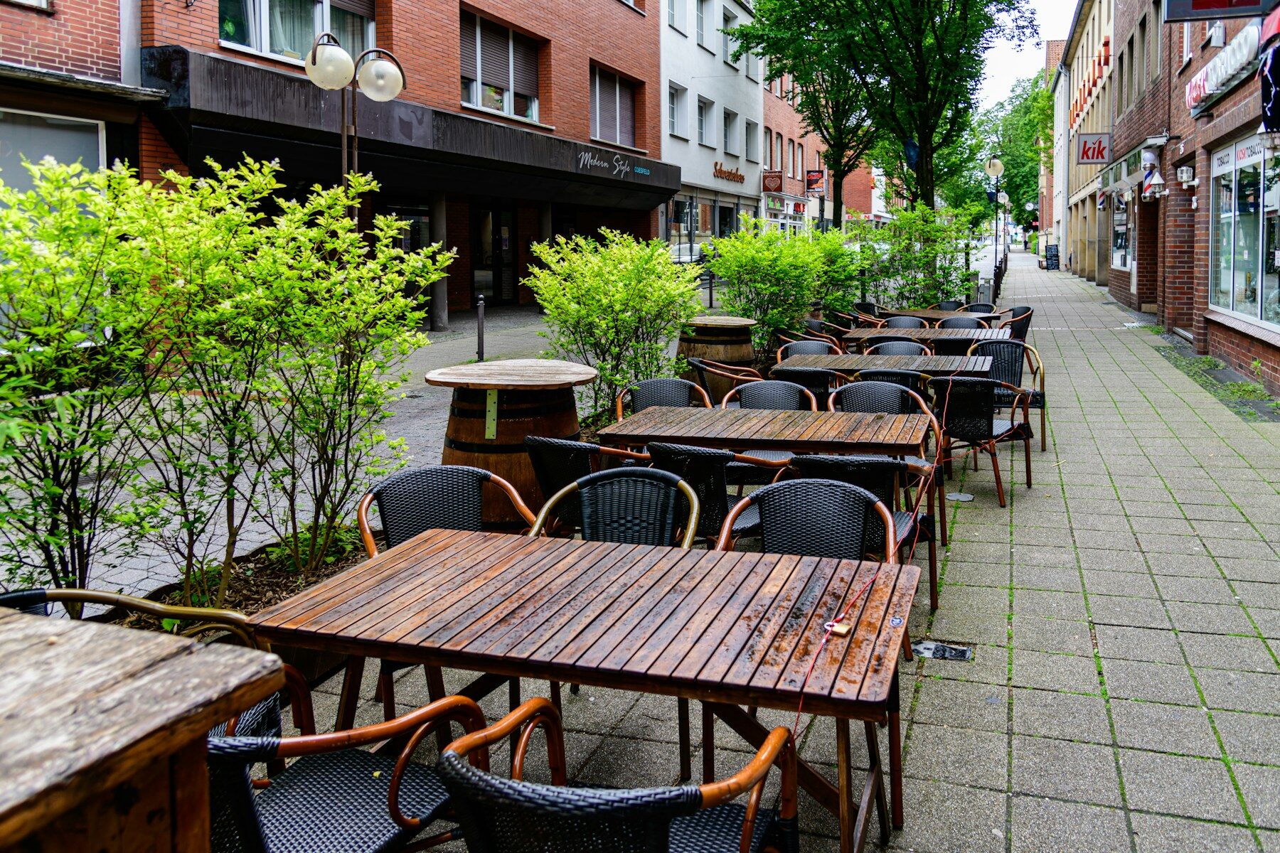 Outdoor cafe tables and chairs on a wet city sidewalk.